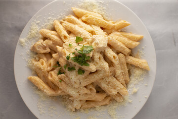 A delightful plate of creamy penne pasta generously topped with cheese and freshly chopped parsley as garnish