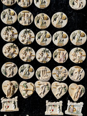 Greek souvenir magnets depicting ancient mythology — gods, warriors, and temples. Relief-style designs of Leonidas, Zeus, and Olympia, crafted in beige and gold tones on a black display background.