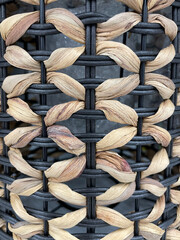 Close-up of woven wicker and black metal basket texture. Natural straw fibers intertwined with dark metal bars create a modern rustic pattern, handmade craft background, macro detail.