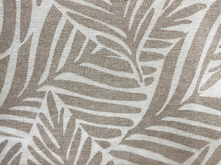 Beige and white fabric texture with tropical palm leaf pattern. Close-up of textile surface with natural woven structure, modern botanical design background for interior or fashion use.