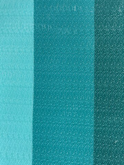 Blue and turquoise fabric texture with vertical stripes. Close-up of woven textile surface showing detailed thread pattern and smooth color gradient, background for design and decor.