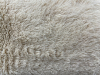 Close-up of soft beige fur texture. Fluffy wool surface with natural fibers, cozy and warm background for textile, fashion, upholstery, or animal-related design projects.