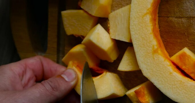 Man cuts orange pumpkin in the kitchen at home preparing Thanksgiving dinne