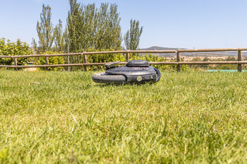 Electric unicycle lies on the green lawn against a wooden fence