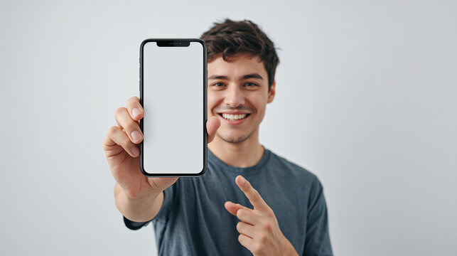 Young man holding smartphone with blank screen, pointing at it with a smile