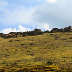 Rocky hillside in a sunny landscape with scattered clouds under a blue sky during midday