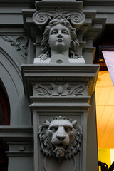 closeup of a facade with a lions head, a womans head on a column and a bit of an arch