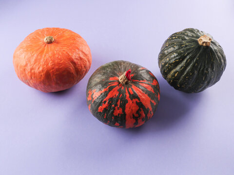Three colorful pumpkins on purple background