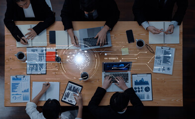 A group of professionals engage in a collaborative business meeting focused on data analytics and innovation, utilizing laptops and digital tools in a modern office environment. Trope