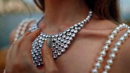 Woman wearing a diamond necklace touching jewelry on her neck and chest close-up of luxury pearls and gems fashion accessory detail elegant glamour concept for special occasions or celebrations