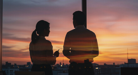 Dynamic business partners strategizing at sunset with city views from office windows, planning future success and growth in a modern, professional environment