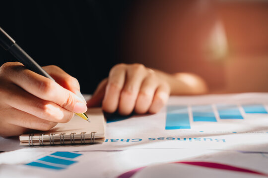 Data analysis concept. Business professional analyzing charts and graphs while taking notes in a notebook with a focus on data and strategy development