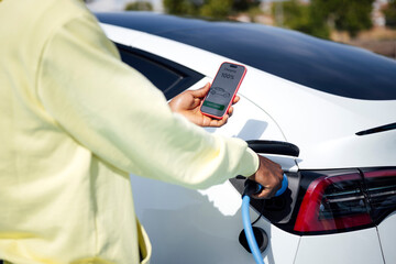 Man charging electric car using smartphone application