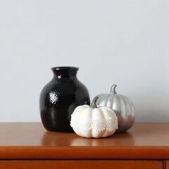 Elegant Black Vase with White and Silver Pumpkins on Wooden Surface