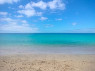 Obraz premium Calm Atlantic Ocean along the coast of Fuerteventura, Canary Islands. Crystal-clear turquoise water, gentle waves and bright sunlight create a peaceful tropical atmosphere.
