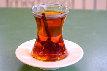 Close-up of traditional Turkish tea in a slim-waisted glass. Enjoyable tea on a white plate....