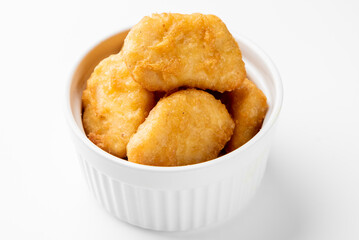 Crispy golden chicken nuggets in a white bowl, top-down view. Fried fast food snack, appetizing texture, suitable for menu, advertising, or culinary content.