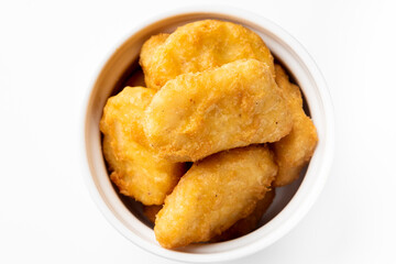 Crispy golden chicken nuggets in a white bowl, top-down view. Fried fast food snack, appetizing texture, suitable for menu, advertising, or culinary content.