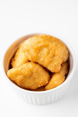 Crispy golden chicken nuggets in a white bowl, top-down view. Fried fast food snack, appetizing texture, suitable for menu, advertising, or culinary content.