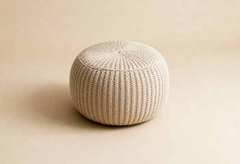 Round knitted pouffe stool in minimal studio setting with soft lighting