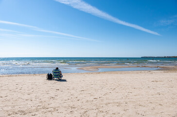 Backview of a Person Sitting on a Beach in Sandbanks Provincial Park, Lake Ontario, in the Fall