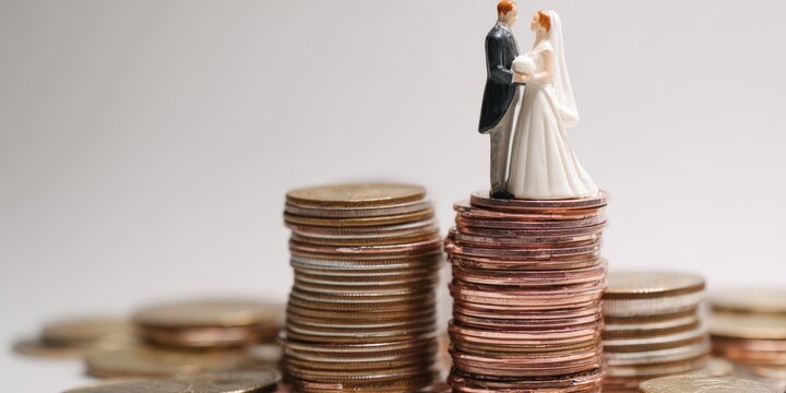 Wedding couple figurines on coin stacks representing high cost