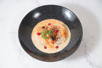 Dahi Baray or bhalla Yogurt Lentil Fritters Garnished with Pomegranate and Spices in bowl isolated on marble background closeup view