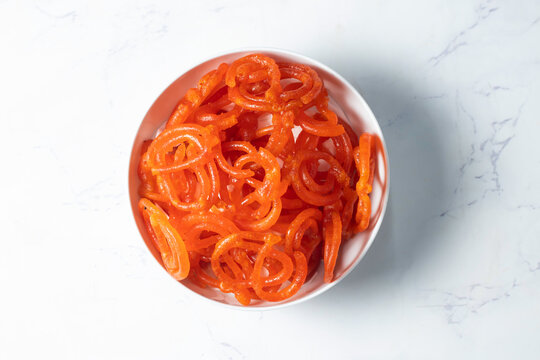 crispy orange Jalebi classic Indian sweet for Diwali and festivals in bowl on marble background top view of dessert