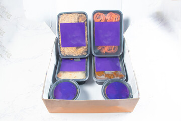 Sealed Iftar Meal Box Takeout Containers with Biryani, Paratha, Beef Curry, Chicken Tikka, and Jalebi Dessert Mockup isolated on marble background side veiw