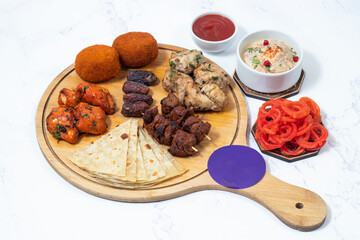 Appetizer Platter Mixed South Asian Kebabs, Rolls, Paratha, Dahi Baray, Malai tikka boti, chicken tikka, Ketchup, Dates, and Dessert Feast on wooden board side view