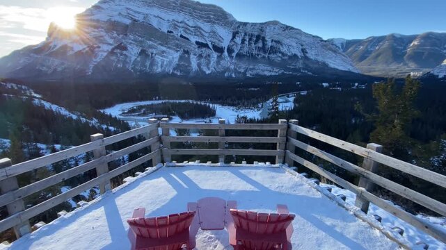 Sunrise tracking shot above red chairs overlooking Bow Valley Rundle Mountain In Banff National Park Canada.
