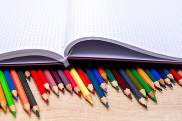 Obraz premium Colored pencils and a notebook