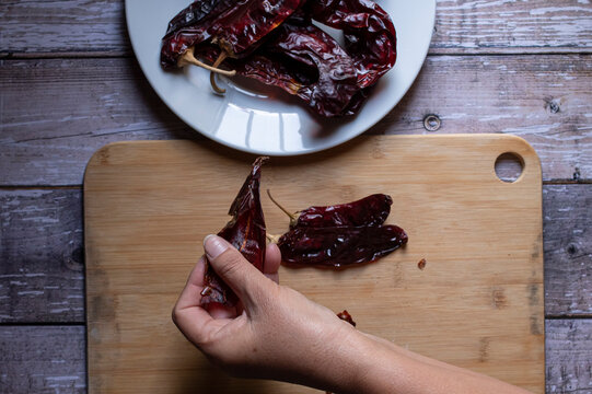 Manipulacion de alimentos, manejo de comida en la cocina, manos quitandole las semillas a unos chiles secos guajillo