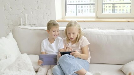 Kids laugh while playing with tablet and smartphone at home - Powered by Adobe