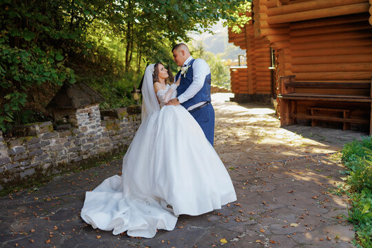 Couple embraces in wedding attire at a rustic location surrounded by nature