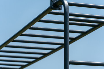 Naklejka premium Dark gray metal monkey bars against a clear blue sky in an outdoor park setting