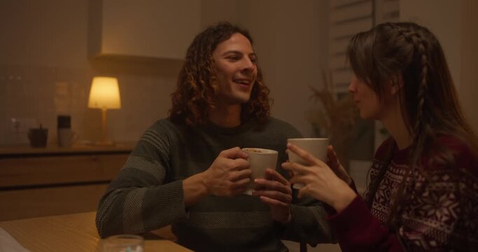 Couple enjoys warm drinks and intimate conversation during cozy evening at home