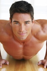 Obraz premium Athletic young caucasian male performing push-up exercise indoors