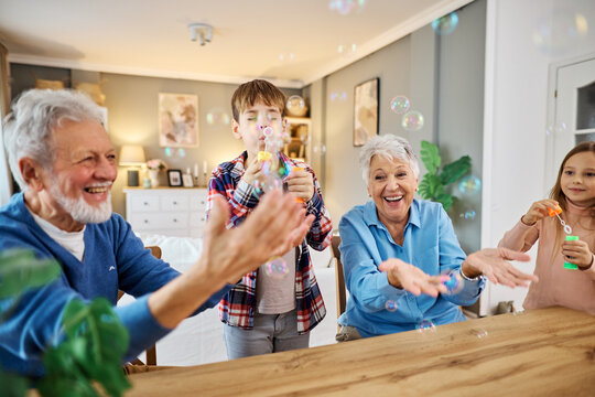 Portrait of grandparents and grandchildren having fun  blowing soap  bubbles together at home