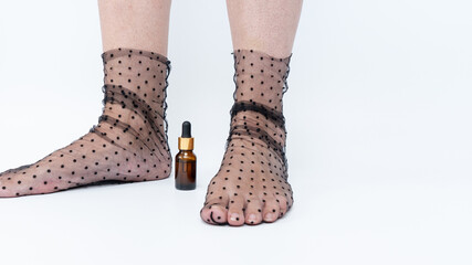 Sore, heavy legs and tired feet in sheer polka dot stockings beside a small amber bottle,...