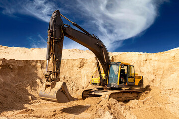 Heavy Excavator Digging Sand at Construction Site Under Blue Sky