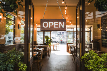 Open sign hanging on café door at restaurant entrance, symbol of small business reopening