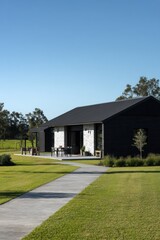Obraz premium A contemporary countryside home is beautifully situated amidst lush greenery, under a radiant blue sky, showcasing the charm of midday simplicity