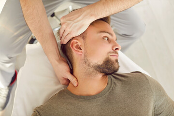 Close-up photo of adult Caucasian male patient in manual therapy office during osteopathic session....