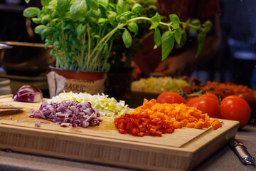 Vibrant chopped vegetables on a wooden cutting board with fresh basil ready for cooking