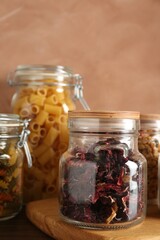 Glass jars with different products on wooden table, closeup