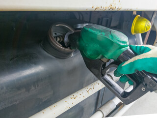 給油所で給油ノズルを持った手が写るトラックの軽油の燃料の給油をしているのイメージ