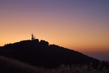 夕焼け空と電波塔が立つ秋の山並み