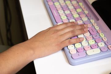 Female feminie hand types on the colorful office keyboard entering data for the company