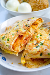 Chinese breakfast (Jian Bing) eggy pan cake stuffed with bacon and potato threads. Eggs blurred at background.